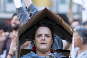 Mulher com casa de cartão na cabeça protesta em Lisboa