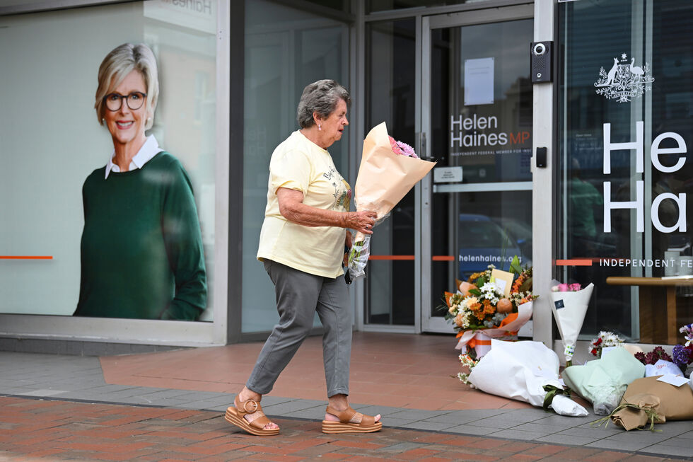 Uma mulher deposita flores junto ao gabinbete de Helen Haines